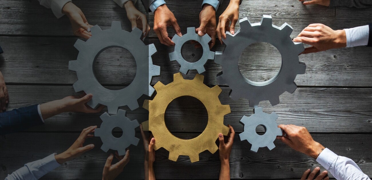 Multiple sets of hands holding gears